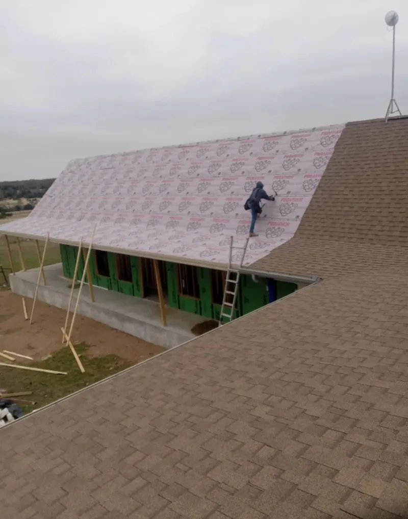 Worker preparing underlayment for a metal roof installation in The Meadows